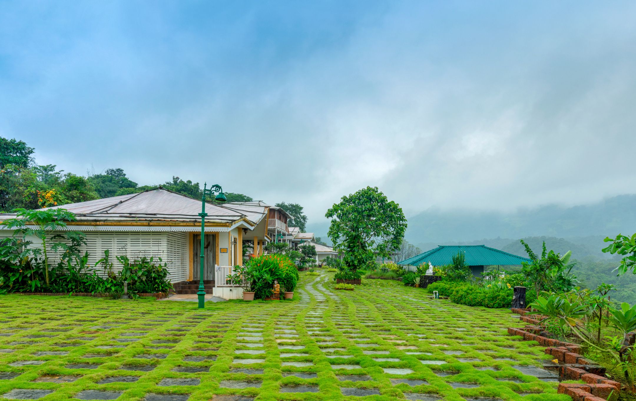 A traditional building with a tiled roof, surrounded by lush greenery and a stone pathway.