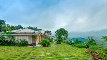 A traditional building with a tiled roof, surrounded by lush greenery and a stone pathway.