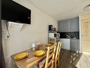 A compact kitchen with a dining area, including a table set for four with yellow plates and wine glasses. - Estrella - Les 3 Vallées - Les Ménuires (Les Menuires)