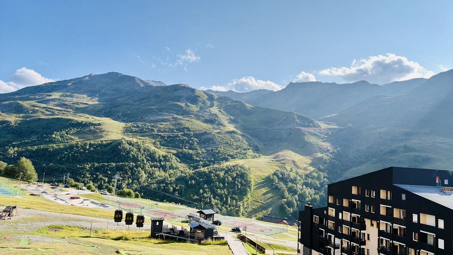 A mountainous landscape with a modern building featuring multiple floors and balconies.