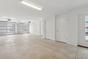 Un garage spacieux et bien éclairé, doté de nombreux placards de rangement et d’un intérieur propre et blanc.
