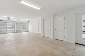 Eine geräumige, gut beleuchtete Garage mit zahlreichen Stauraumschränken und einem sauberen, weißen Innenraum.