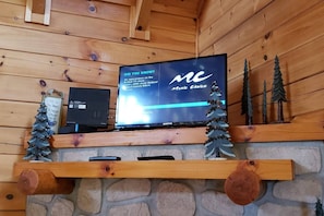 Ein Fernseher auf einem Holzregal, darunter eine Steinwand.