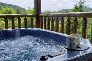 Ein Whirlpool mit zwei Tassen auf einem Tisch, umgeben von einer Holzterrasse und einer schönen Aussicht.