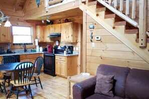 Ein Holzblockhaus-Innenraum mit Küche, Essbereich und einer Treppe.
