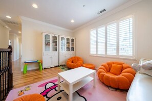 A children's playroom with a white table, orange chairs, a bookshelf, and a window with blinds. - 19ppl 6b4b Perfect for Big Group Garage Parking (Monterey Park)