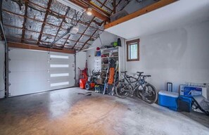 A garage with a concrete floor, a bicycle, a motorcycle, and a red lawnmower. - Lark & Leisure (Bend)