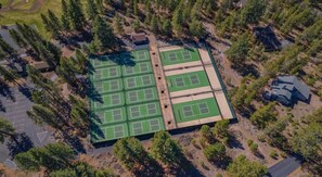 An aerial view of a sports complex with multiple tennis courts surrounded by trees. - Lark & Leisure (Bend)