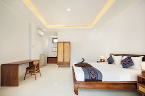 Ein Hotelzimmer mit einem hölzernen Bett, einem Nachttisch, einer Lampe und einem Schreibtisch mit Stuhl.