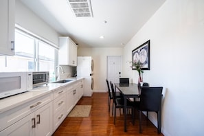 A modern kitchen with white cabinetry, a built-in microwave, and a dining area with a table and chairs. - 22ppl 7b5b Perfect family&biz stay Garage Gated (Monterey Park)