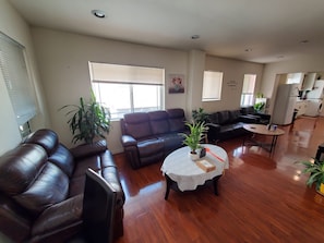 A living room with a sofa, a coffee table, and a dining table. There are potted plants and a painting on the walls. - 22ppl 7b5b Perfect family&biz stay Garage Gated (Monterey Park)