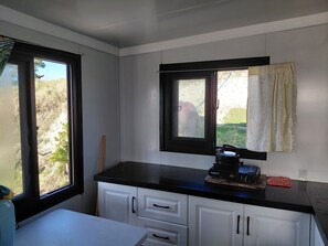 A kitchen with white cabinets, a black countertop, and a window with a view of greenery.