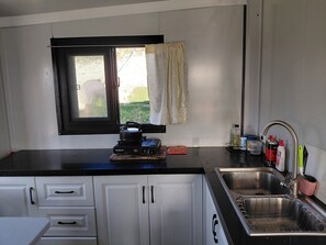 A compact kitchen with a gas stove, a sink, and cabinets.