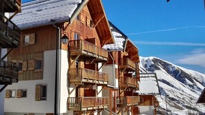 A wooden chalet with multiple balconies and a mountain backdrop. - Sybelles Ski Area | Sleeps 5 | Ski-in Paradise (Saint Sorlin d'Arves)