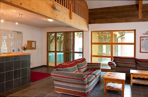 A spacious lobby with a high ceiling, wooden beams, a reception desk, patterned sofas, and large windows. - Sybelles Ski Area | Sleeps 10 | Slope-side Comfort (Saint Sorlin d'Arves)