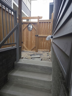 A wooden gate with a decorative metal design, leading to a gravel area. - Cozy 2-bedroom basement apartment (Calgary)