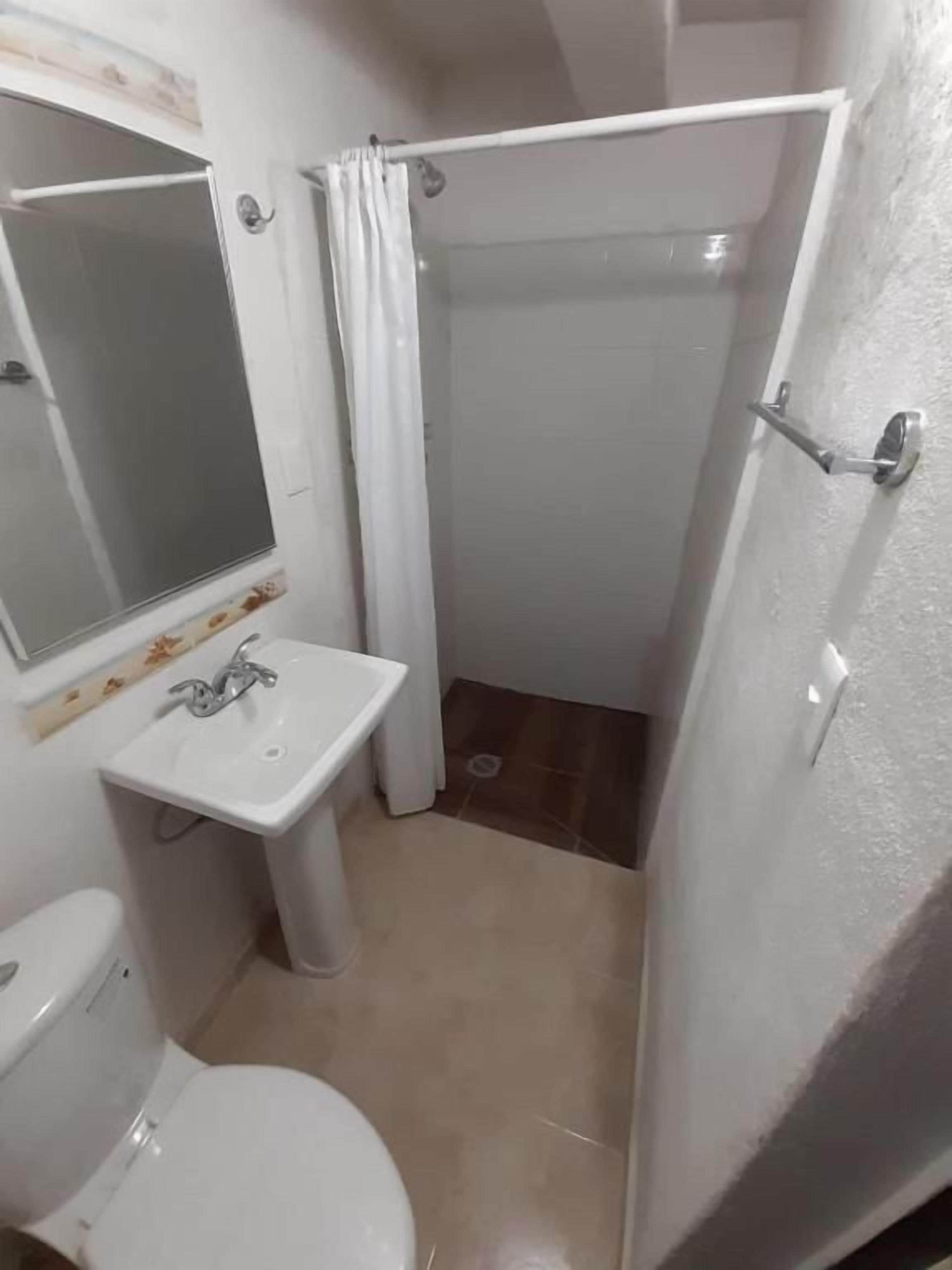 Une salle de bain avec des toilettes, un lavabo et une douche.