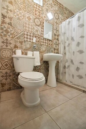 Un baño con inodoro, lavamanos y azulejos estampados.