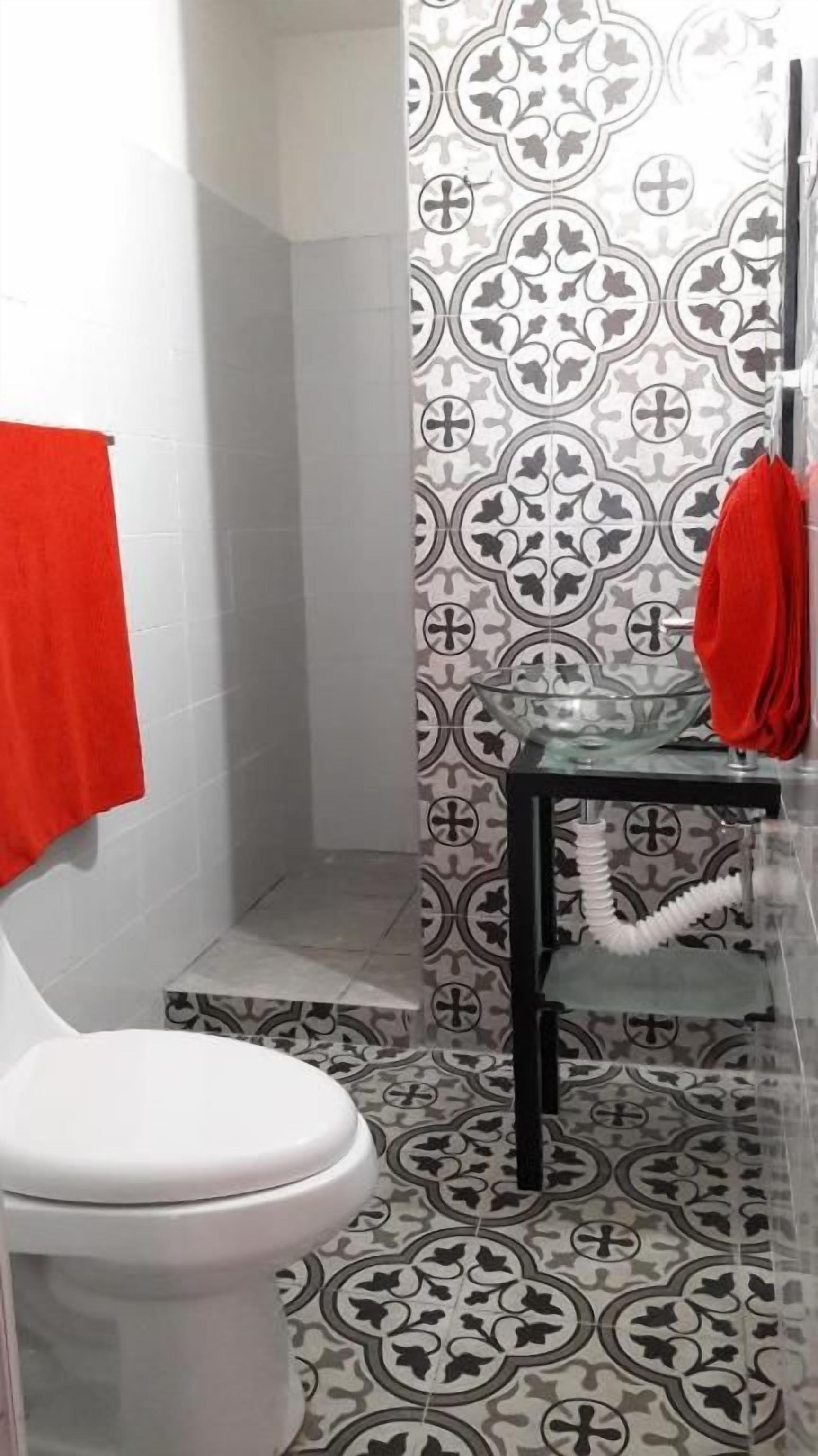 Un baño con inodoro, zona de ducha y lavamanos con toallero.