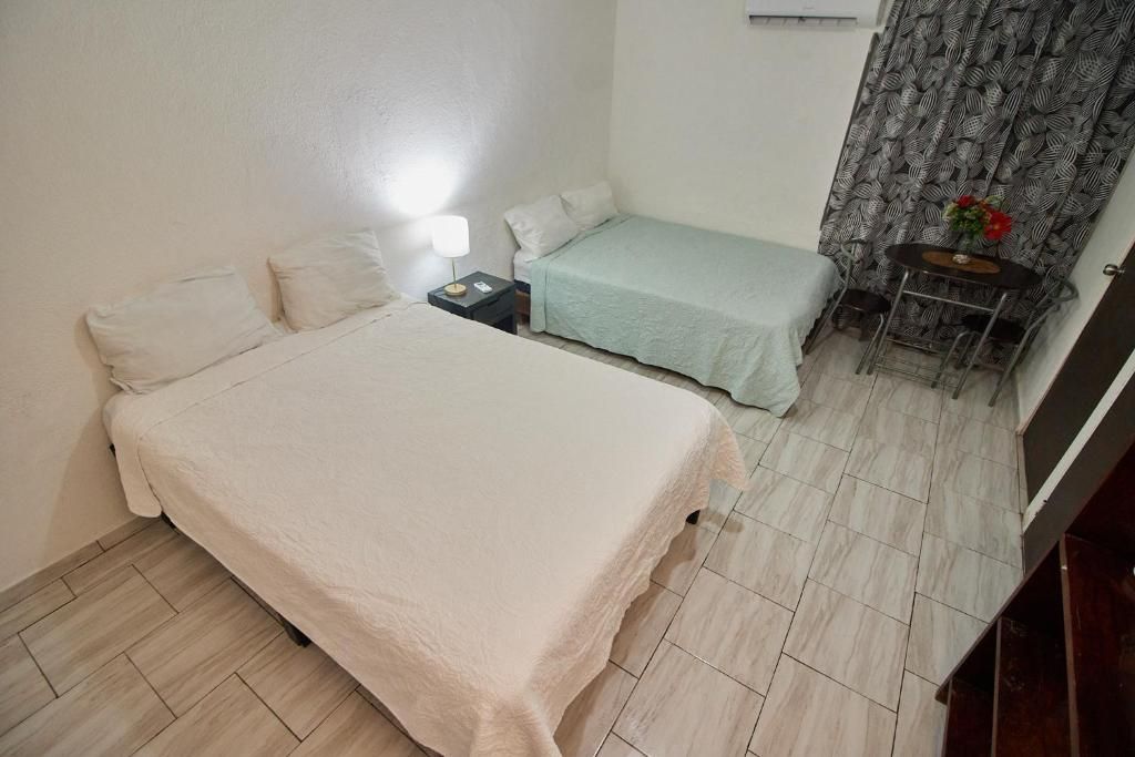Un dormitorio con cama, mesita de noche y una pequeña mesa con un florero.