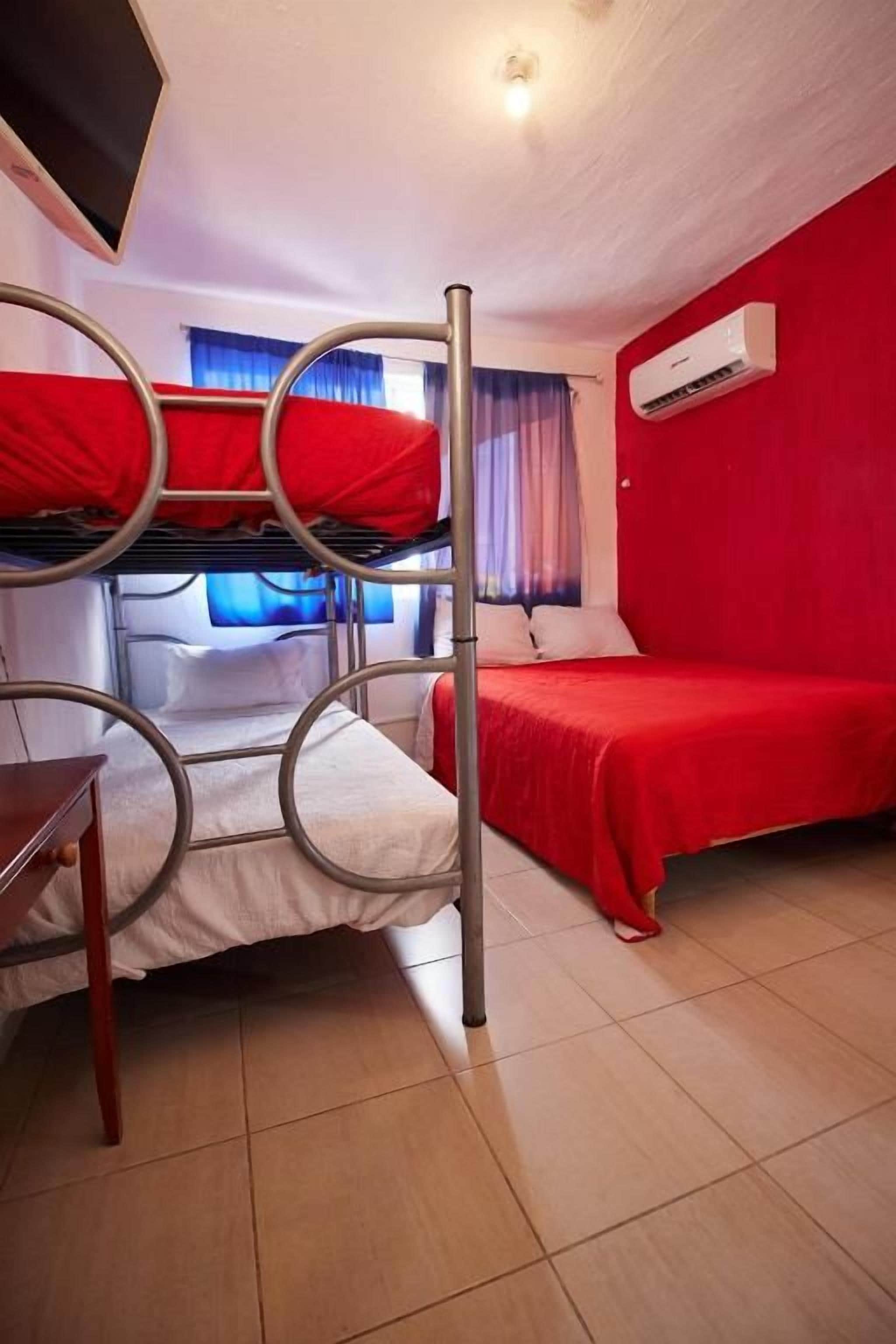 Una habitación con literas, un escritorio y un ventanal con cortinas.