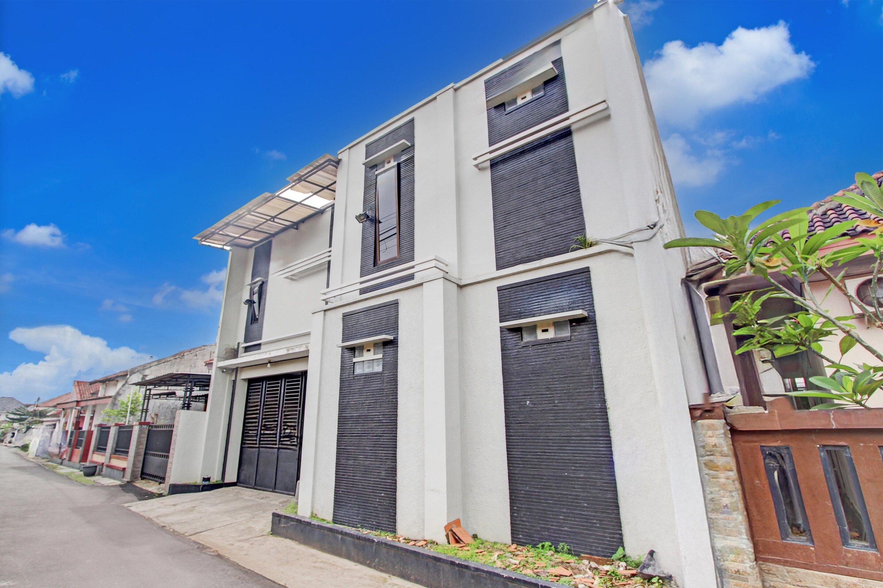 A modern two-story building with a flat roof, large windows, and a gated entrance.