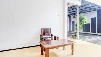 A room with a wooden table and a chair, a tiled floor, and a view of a building through an open door.