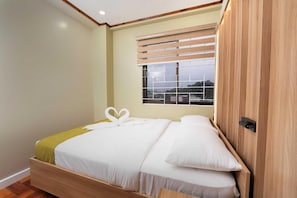 A single bed with a wooden frame, a window with blinds, and a view of the outside. - HIGHLAND NEST (Baguio)