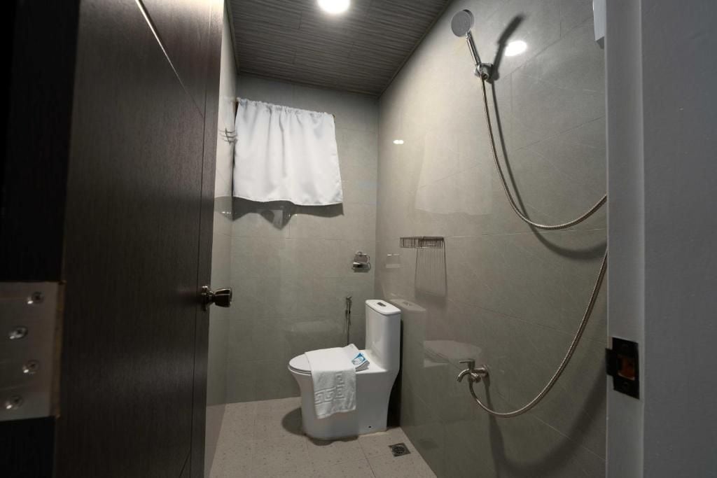 Un baño pequeño y cerrado con inodoro, ducha y una toalla colgada en la pared.