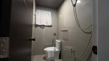Un baño pequeño y cerrado con inodoro, ducha y una toalla colgada en la pared.