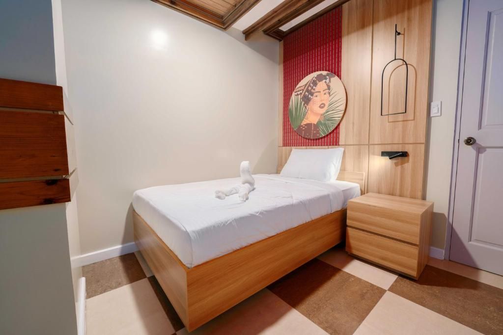 A bedroom with a wooden bed, a nightstand, a red accent wall, and a door.