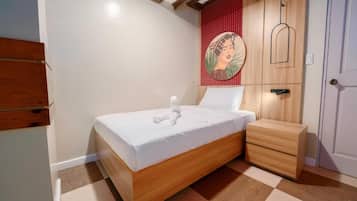 A bedroom with a wooden bed, a nightstand, a red accent wall, and a door.