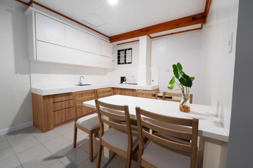 A modern kitchen with white cabinetry, a wooden dining table, and chairs.