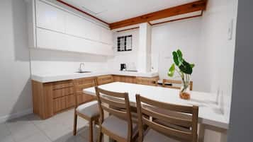 A modern kitchen with white cabinetry, a wooden dining table, and chairs.