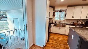 A kitchen with white cabinets, a stainless steel sink, and a wooden floor.