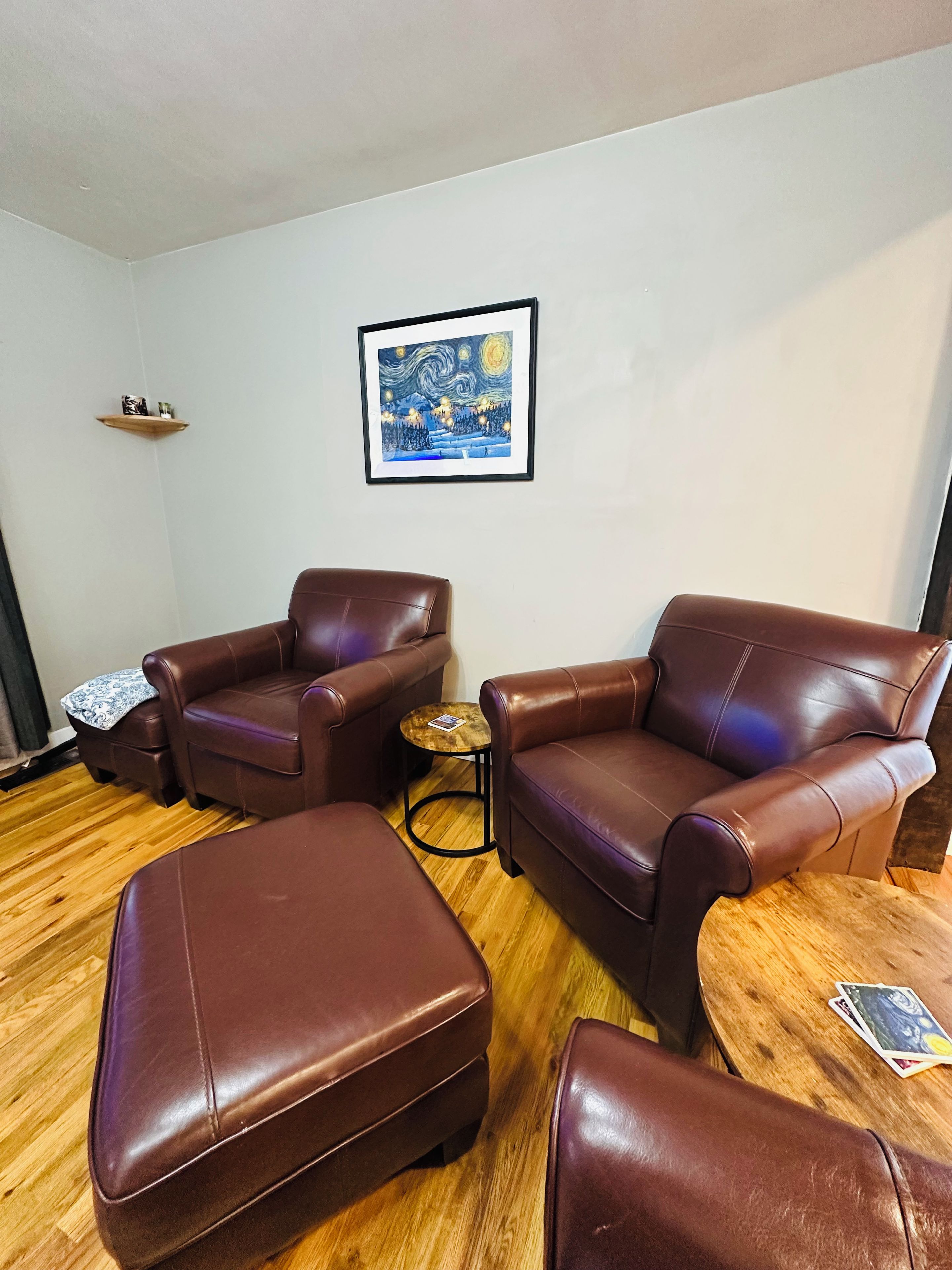A living room with leather sofas, a coffee table, and a framed artwork on the wall.