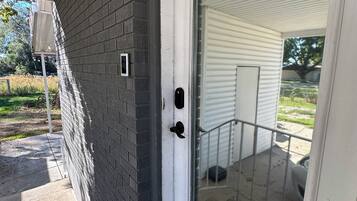 A house entrance with a glass door, a brick wall, and a porch area.
