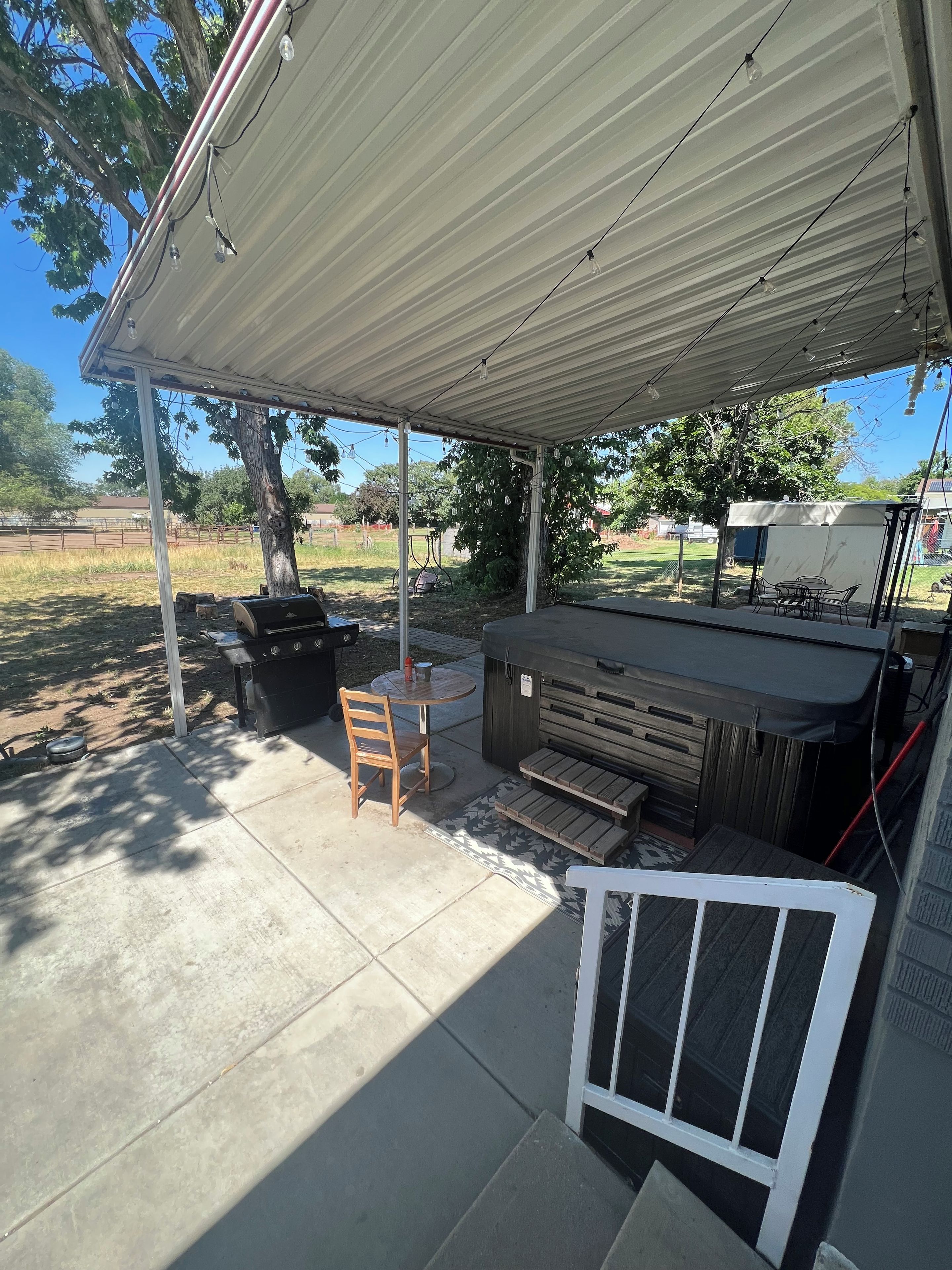 An outdoor patio with a covered seating area, a grill, and a tent.