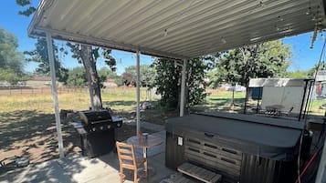An outdoor patio with a covered seating area, a grill, and a tent.