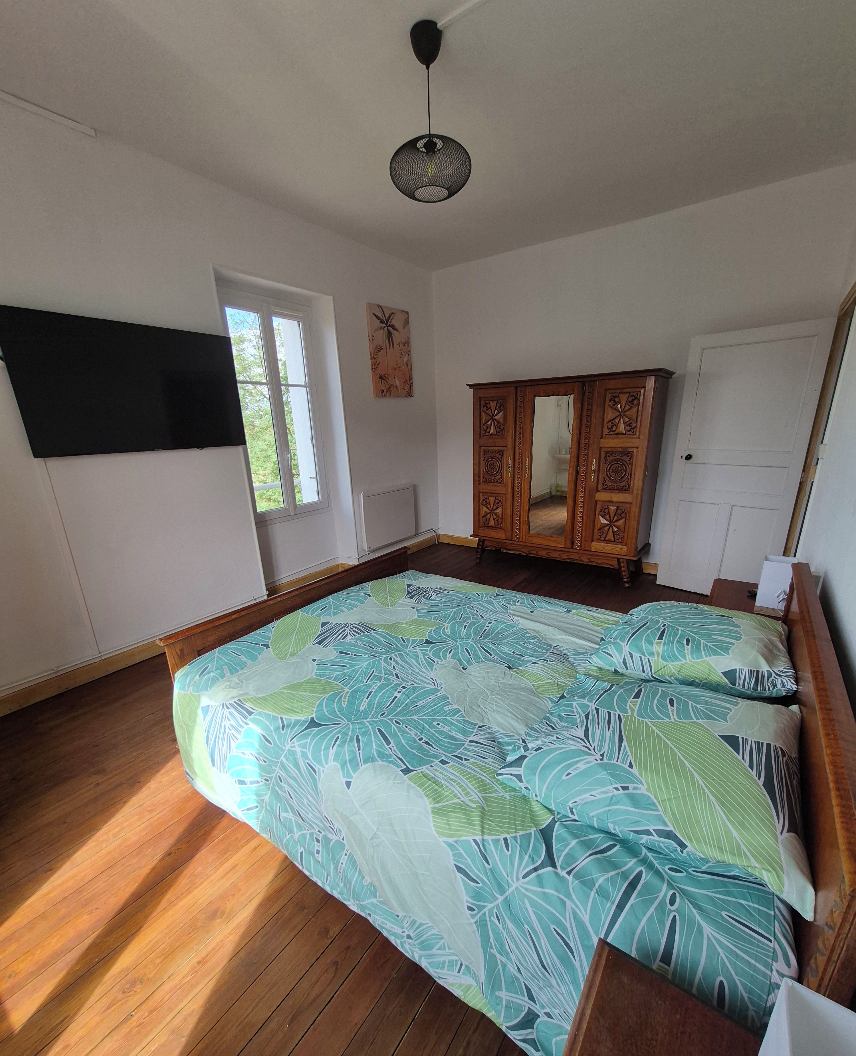 A bedroom with a bed, a wardrobe, a window, and a ceiling fan.