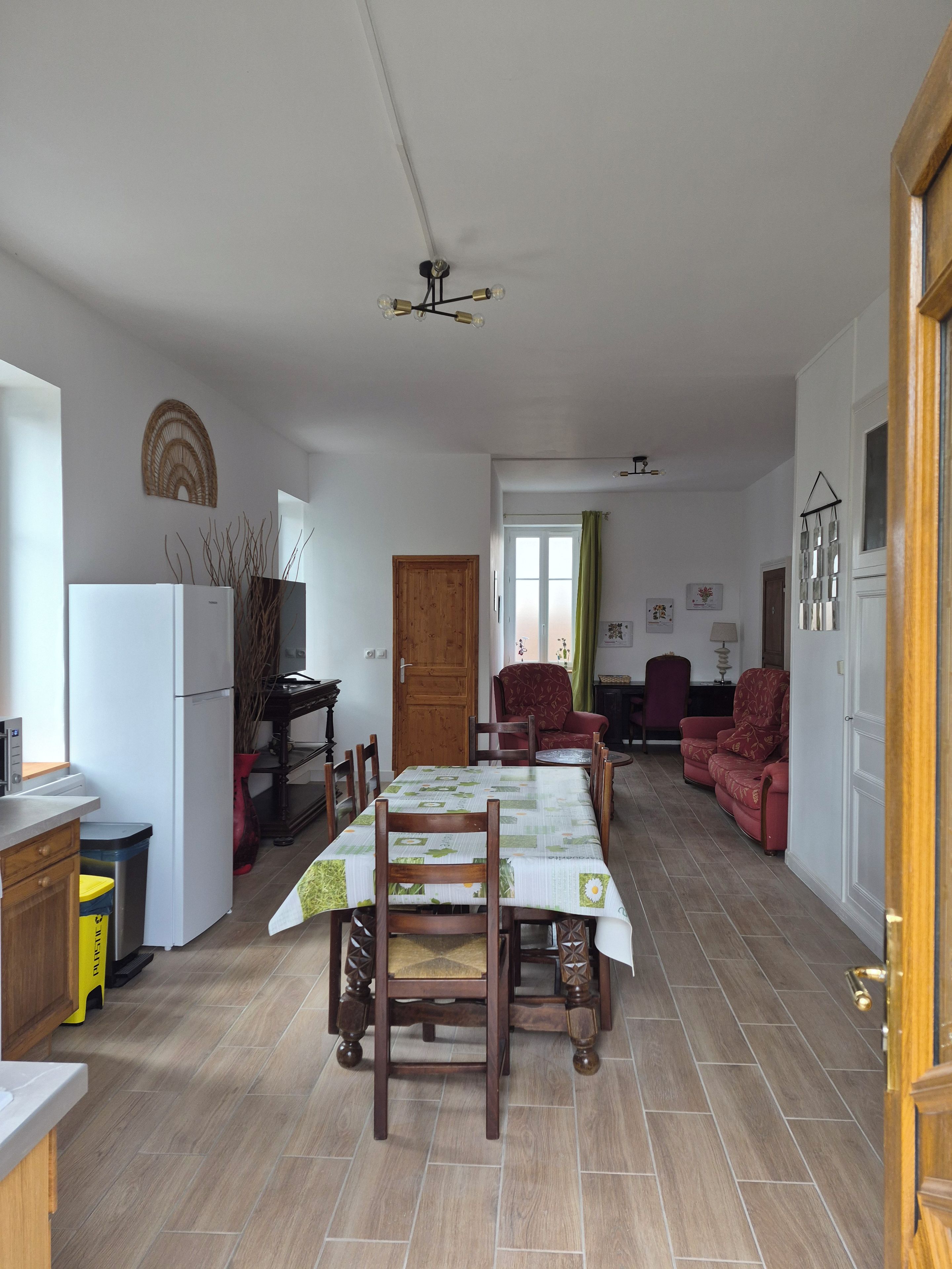 A spacious kitchen with a dining table, chairs, and a refrigerator.