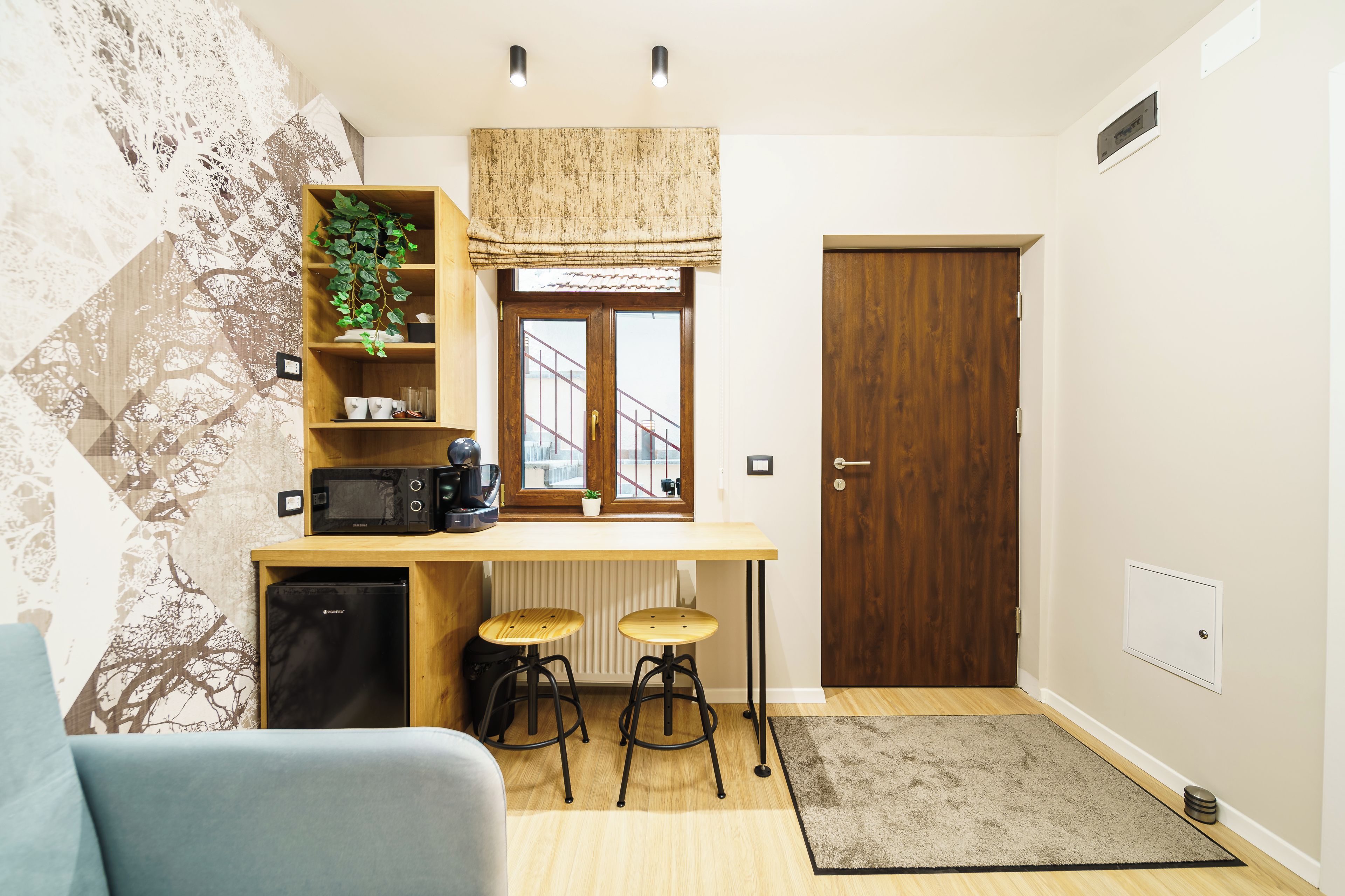 Cocina compacta con microondas, cafetera y taburetes.