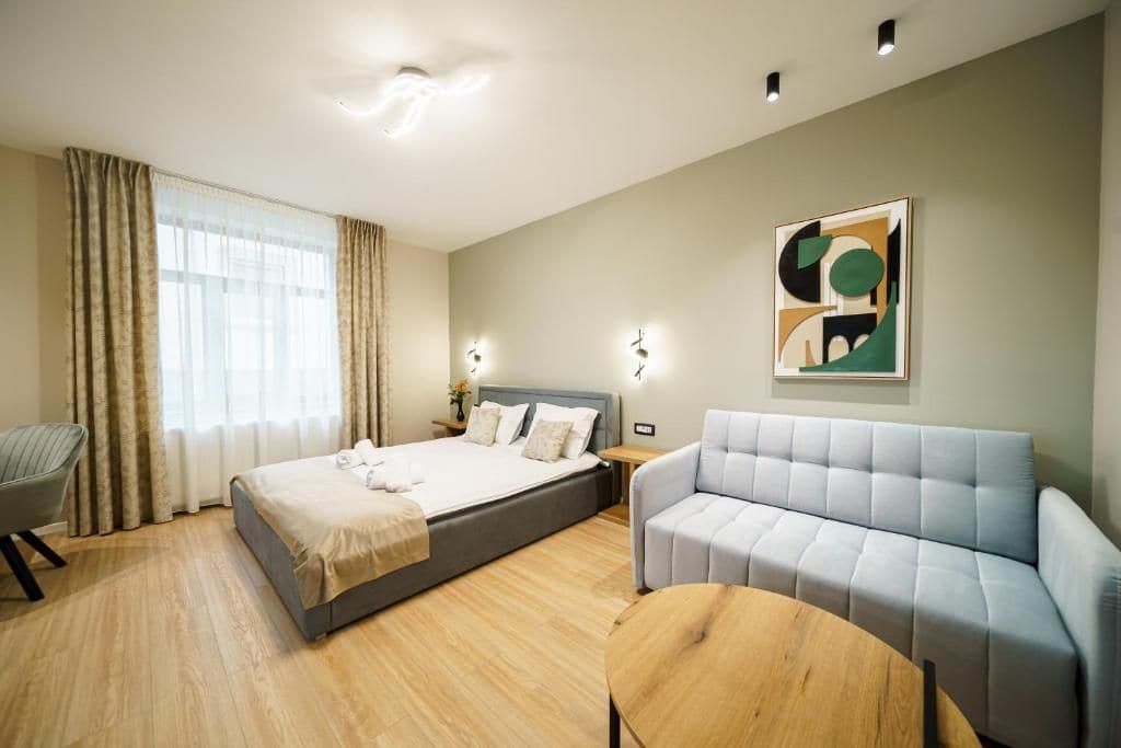 Une chambre d’hôtel moderne, équipée d’un lit, d’un canapé, d’une table basse ronde et d’un tableau au mur.