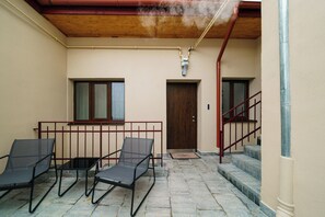 Uma área externa com assentos para dois, teto de madeira e guarda-corpo vermelho.