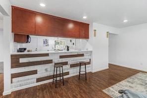 A kitchen with wooden cabinets, a white countertop, and two stools.