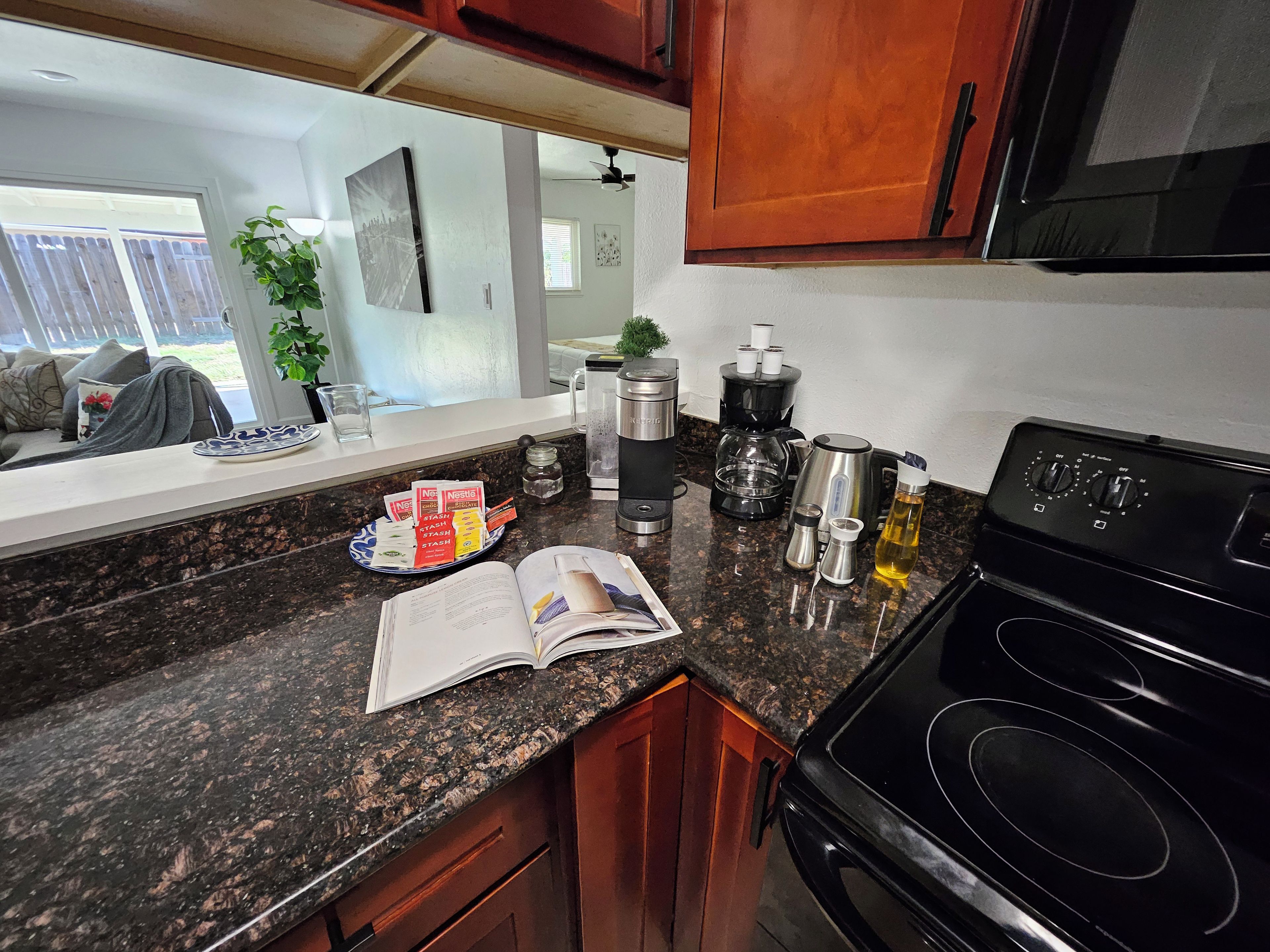 A kitchen with granite countertops, a black stove, and various appliances including a coffee maker and a kettle.