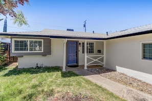 A single-story house with a front door, a small porch, and a mailbox.