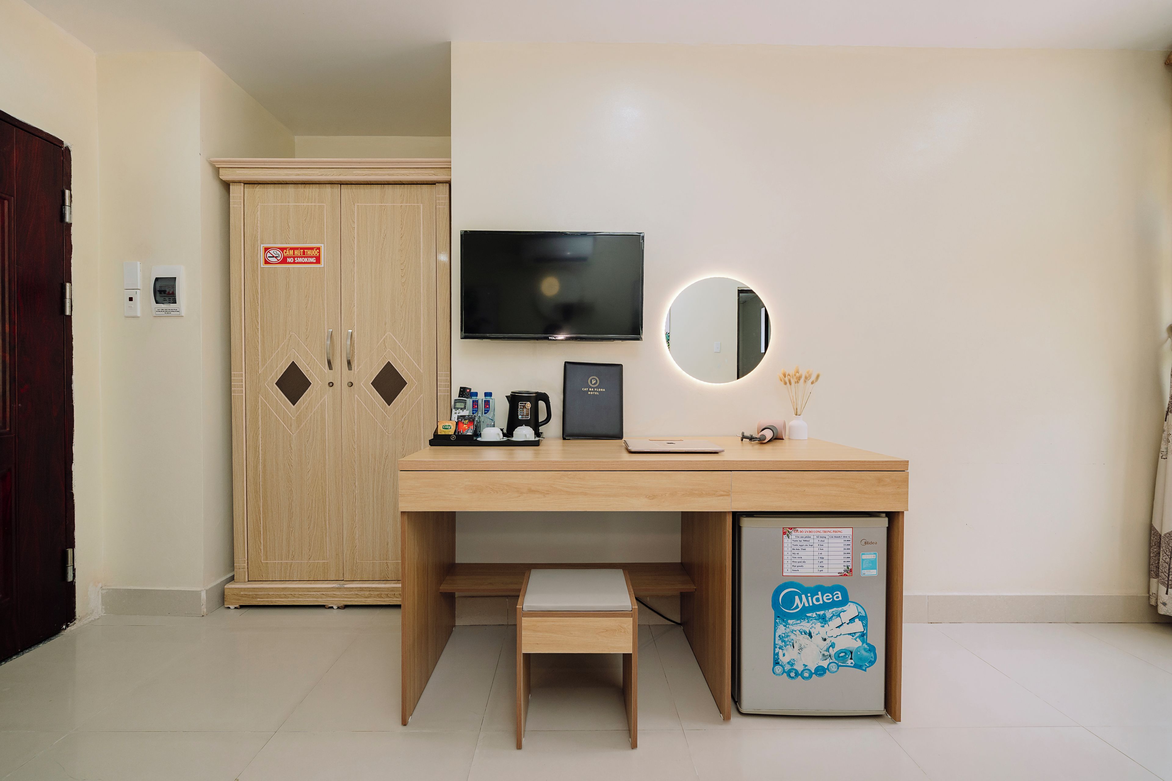 Une chambre d’hôtel équipée d’un bureau en bois, d’une télévision, d’un miroir, d’un mini-bar et d’un réfrigérateur.