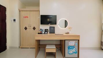 Une chambre d’hôtel équipée d’un bureau en bois, d’une télévision, d’un miroir, d’un mini-bar et d’un réfrigérateur.