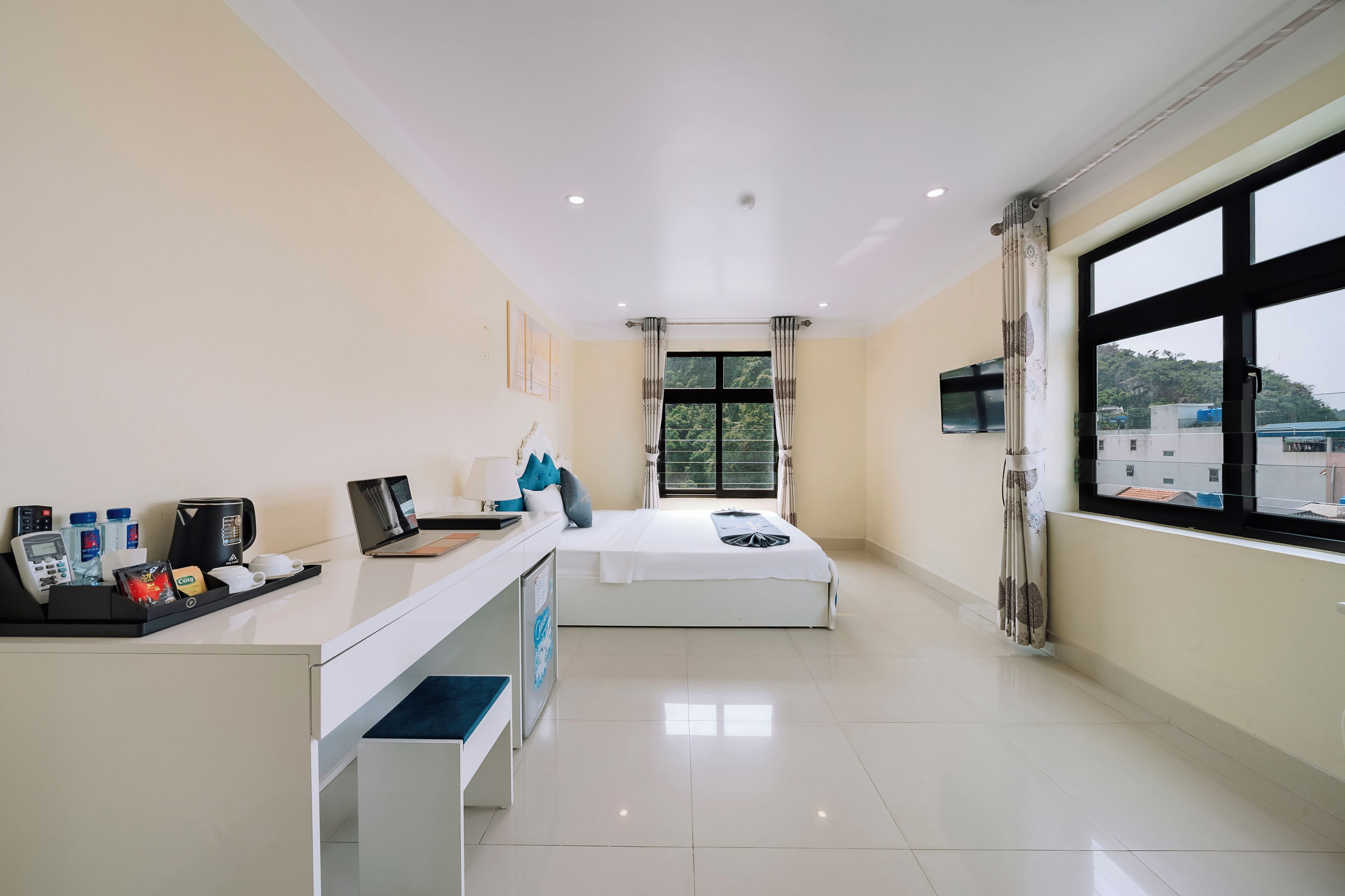 Una habitación de hotel con una cama, un escritorio con una computadora portátil, un teléfono y una cafetera.